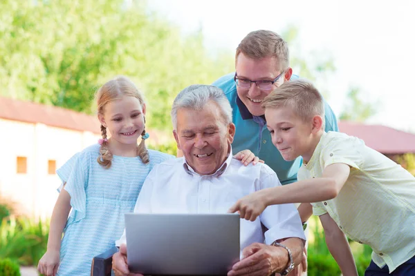 Happy family with grandfather during internet talking on laptop — Stock Photo, Image