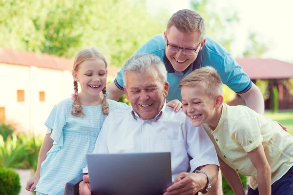 Familia feliz con el abuelo durante Internet hablando en el ordenador portátil —  Fotos de Stock