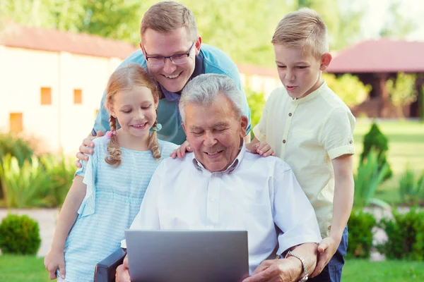 Šťastná rodina s dědečkem během Internetu mluví na laptop — Stock fotografie
