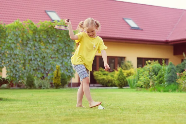 Porträtt av lilla glad flicka som leker barfota badminton på gard — Stockfoto