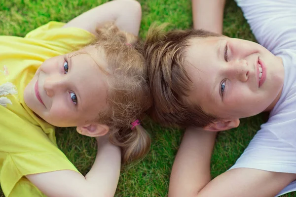 Šťastné děti leží na zelené trávě na zahradě — Stock fotografie