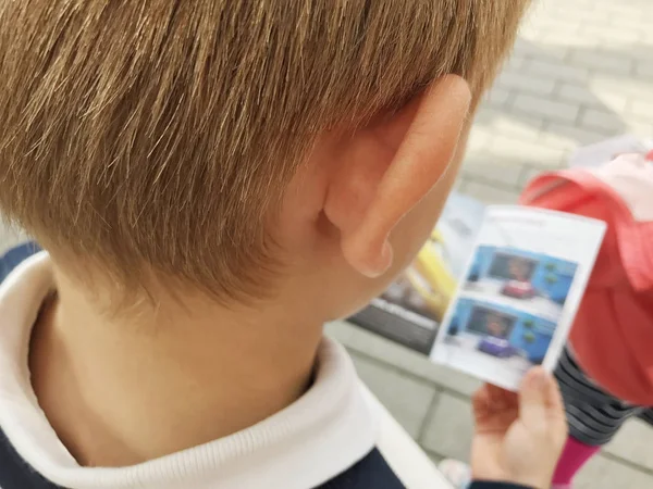 Liten pojke läsa tidningen utomhus. Vy bakifrån. — Stockfoto