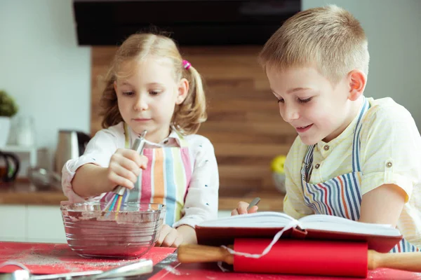 Zwei glückliche Kinder backen Weihnachtsplätzchen in der Küche — Stockfoto