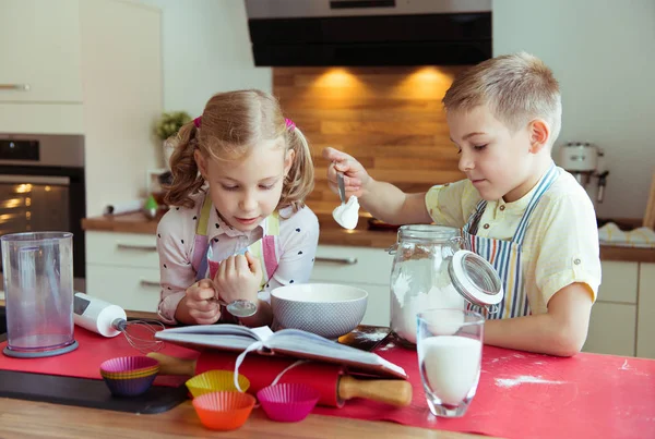 Two happy little and cute children preparing muffins in modern k — Stock Photo, Image