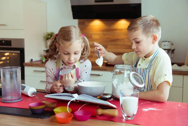 Zwei fröhliche kleine und niedliche Kinder bereiten Muffins in modernem K — Stockfoto