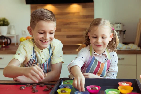 Duas crianças felizes fazendo biscoitos de Natal e muffins no kitch — Fotografia de Stock