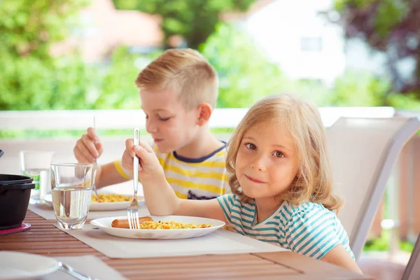 Двое счастливых маленьких детей едят здоровый завтрак дома — стоковое фото
