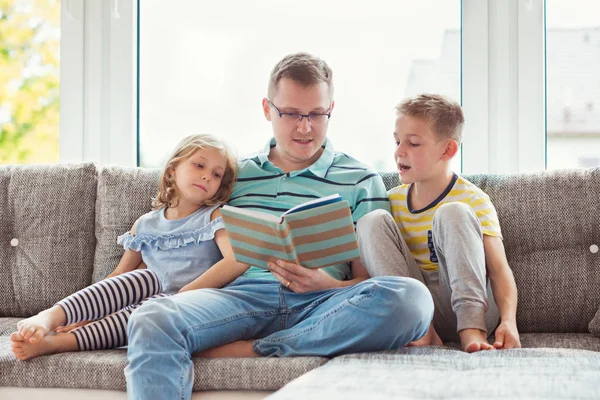 年轻快乐的父亲读书与逗人喜爱的孩子在家 — 图库照片