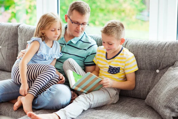 Νέοι ευτυχής πατέρας ανάγνωση του βιβλίου με χαριτωμένα παιδιά στο σπίτι — Φωτογραφία Αρχείου
