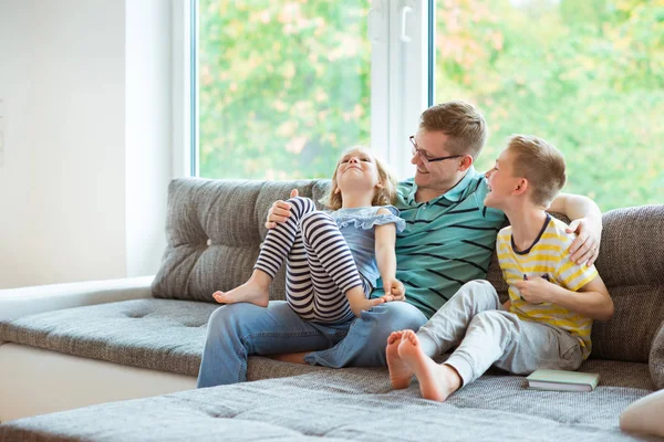 Junger glücklicher Vater liest Buch mit niedlichen Kindern zu Hause — Stockfoto