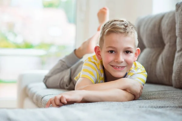 Lycklig skolpojke 9 år gammal liggande på soffan — Stockfoto