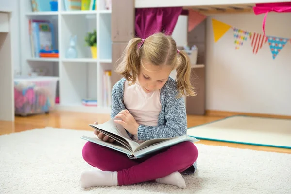 Porträt eines schlauen kleinen Mädchens, das zu Hause Buch liest — Stockfoto