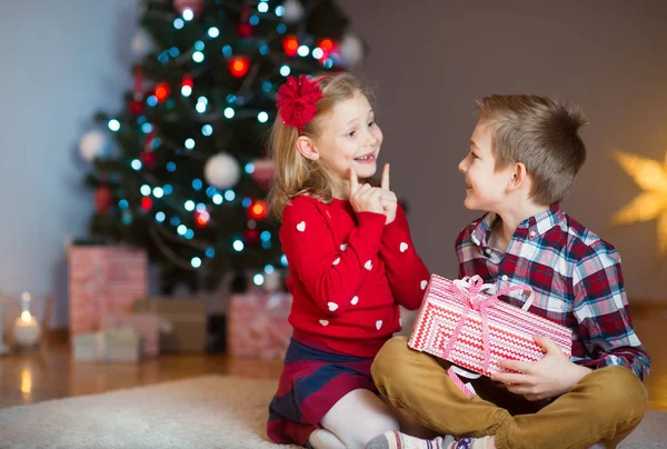 Due bambini felici in vigilia di anno nuovo con regali vicino a Anno nuovo T — Foto Stock