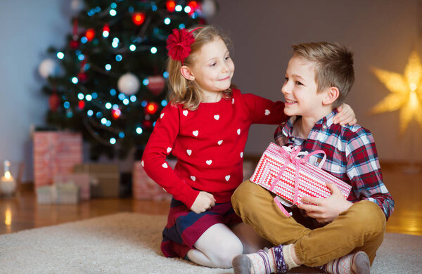 Two happy children in new year eve with presents near New Year T
