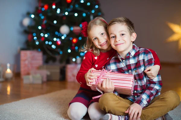 Twee gelukkige kinderen in nieuwe jaar vooravond met presenteert in de buurt van New Year T — Stockfoto