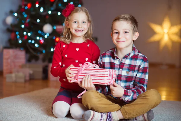 Twee gelukkige kinderen in nieuwe jaar vooravond met presenteert in de buurt van New Year T — Stockfoto