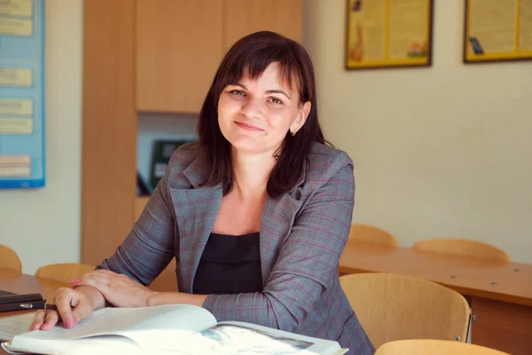 Jolie jeune professeur est assis avec des livres en classe — Photo