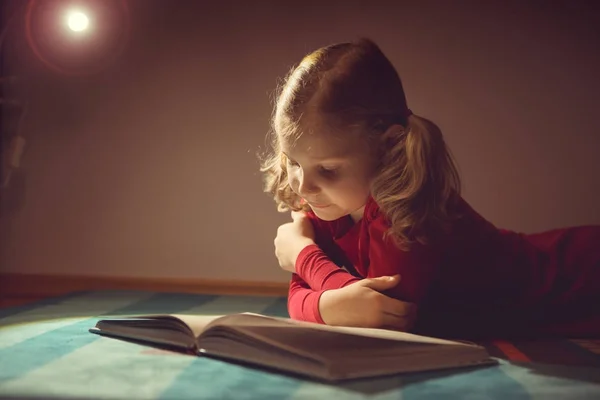 Hübsches kleines Mädchen liest Buch in ihrem Versteck mit Flashli — Stockfoto