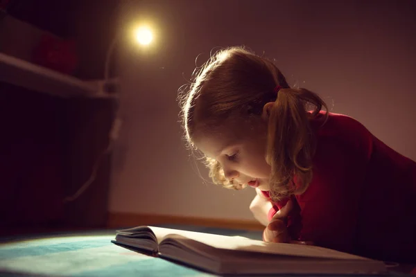 Pretty little girl reading book in her hiding place with flashli — Stock Photo, Image