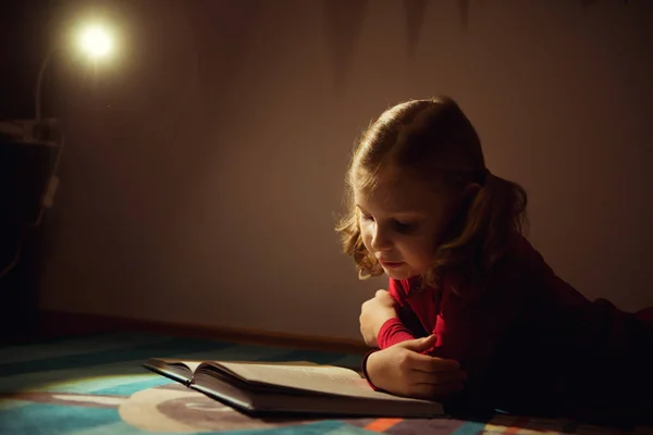 Hübsches kleines Mädchen liest Buch in ihrem Versteck mit Flashli — Stockfoto