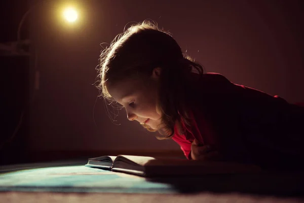 Красивая маленькая девочка читает книгу в своем тайнике с Флэшли — стоковое фото