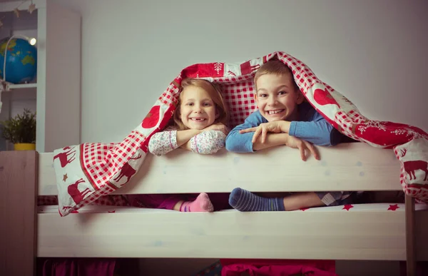 Deux heureux frères et sœurs enfants s'amusent dans un lit superposé — Photo