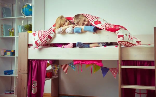 Deux heureux frères et sœurs enfants s'amusent dans un lit superposé — Photo