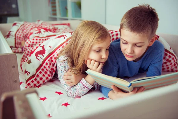 Deux enfants heureux frères et sœurs lisant le livre dans un lit superposé sous vide — Photo