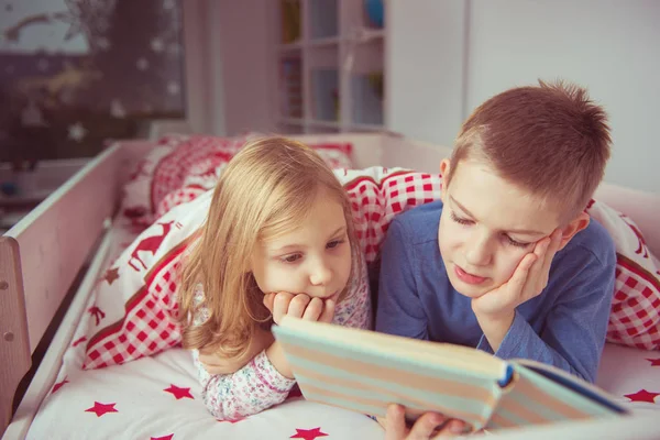 Zwei glückliche Geschwisterkinder lesen Buch im Etagenbett unter einer Decke — Stockfoto