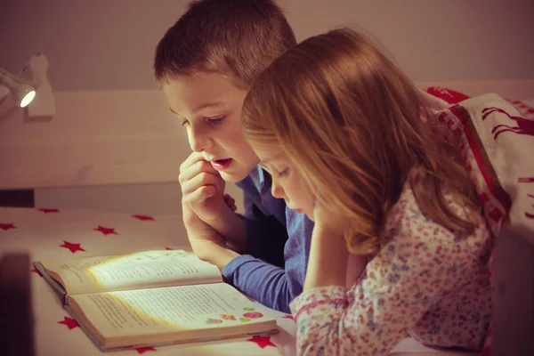 Deux enfants heureux frères et sœurs lisant le livre dans un lit superposé sous vide — Photo