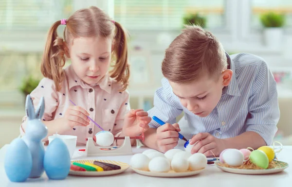 Dos niños felices divirtiéndose durante la pintura de huevos para pascua en —  Fotos de Stock