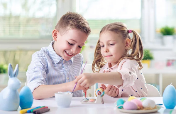 Dos niños felices divirtiéndose durante la pintura de huevos para pascua en —  Fotos de Stock