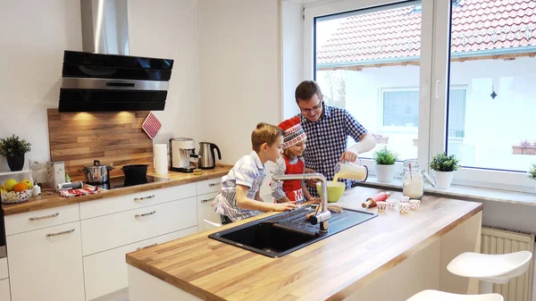 Молодой отец с двумя счастливыми детьми поддерживает кулинарию в современном мире — стоковое фото