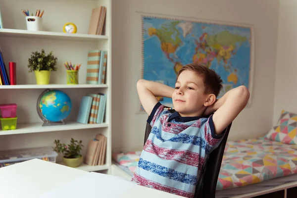 Liten smart skola pojke att göra läxor på skrivbord i rummet — Stockfoto