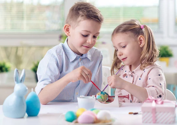 Due bambini felici si divertono durante la pittura uova per Pasqua in — Foto Stock