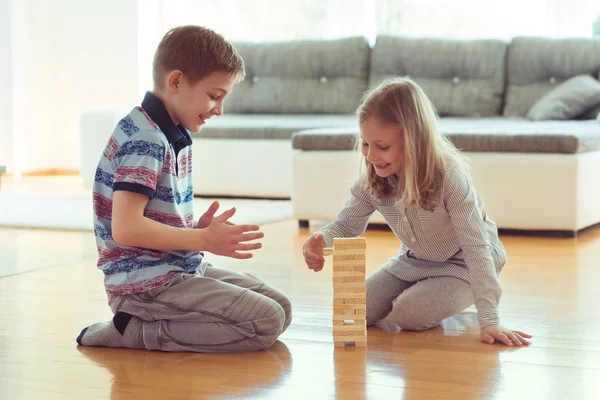 Δύο αδέλφια ευτυχισμένος παίζει ένα παιχνίδι με ξύλινα μπλοκ στο σπίτι — Φωτογραφία Αρχείου