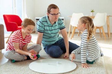Mutlu genç baba iki neşeli kardeşiyle oynuyor.