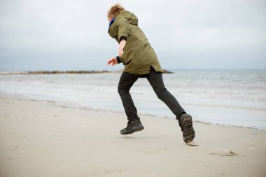 Baltık Denizi 'nin soğuk sularında koşan mutlu genç çocuk.