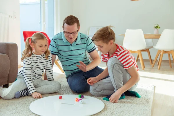 Счастливый молодой отец играет со своими двумя веселыми детьми братьев и сестер — стоковое фото