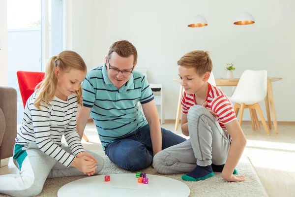 Feliz padre joven juega con sus dos hermanos alegres hijos — Foto de Stock