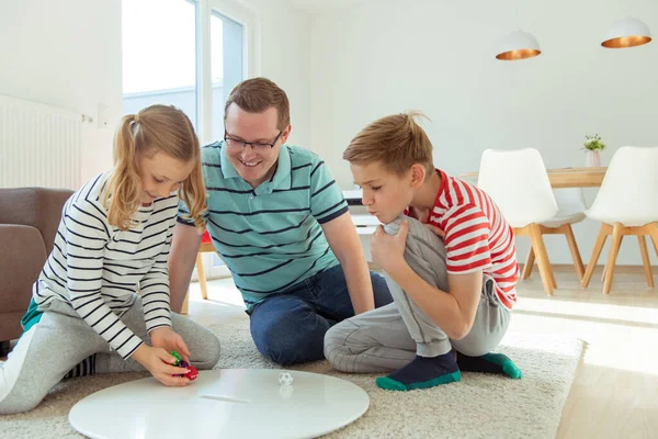 Feliz padre joven juega con sus dos hermanos alegres hijos —  Fotos de Stock