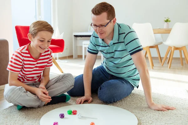 Glad ung far leker med sin tonåring son brädspel med c — Stockfoto