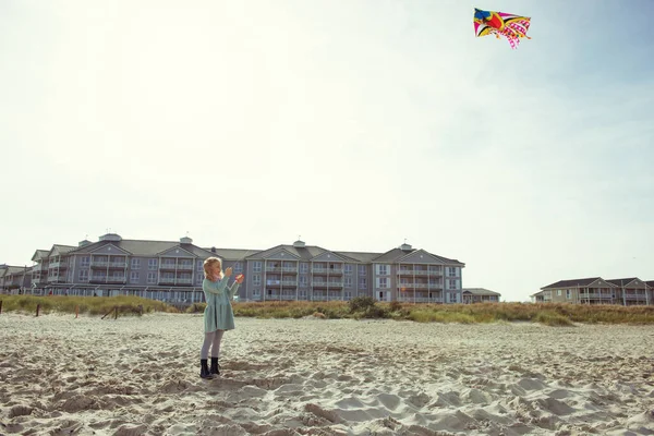Wesoła dziewczynka biegnie w sukience na plaży z latawcem — Zdjęcie stockowe