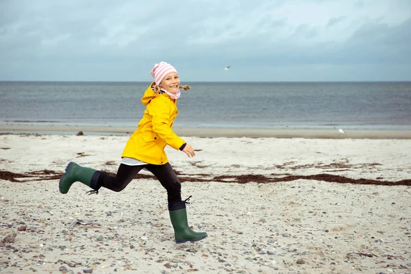 Wesoła dziewczynka biegająca po wodach Morza Bałtyckiego w gumowej bryle — Zdjęcie stockowe