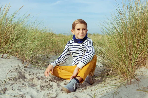 Портрет красивого хлопчика-підлітка, що сидить на білому піску на пляжі — стокове фото