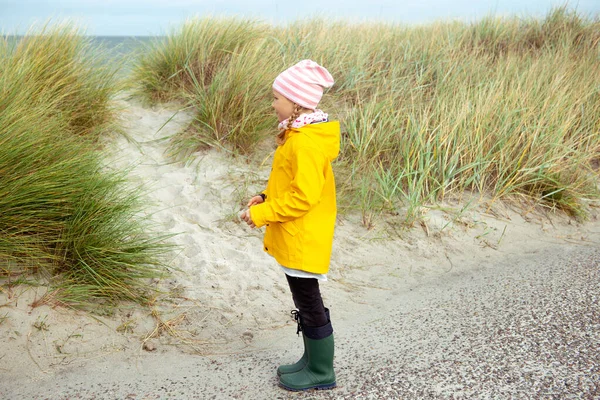 Cheerful little girl staying on beach of Baltic sea at windy wea — Stock Photo, Image