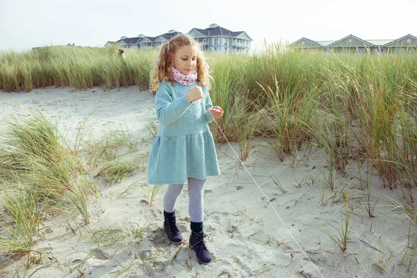 Портрет веселої маленької дівчинки в сукні на пляжі з повітряним змієм — стокове фото