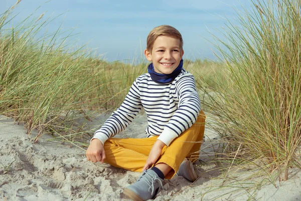 Porträtt av stilig tonåring pojke sitter på vit sand på stranden — Stockfoto