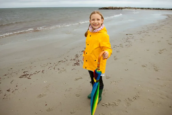 Veselá holčička zůstává na pláži s barevným deštníkem na — Stock fotografie