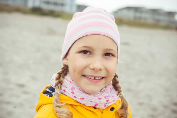 Retrato de niña en chaqueta amarilla en la playa en la nube lluviosa —  Fotos de Stock